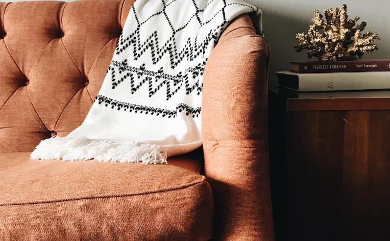 burnt orange couch with fall accent blanket in a living room